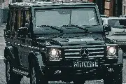 Chauffeur greeting a passenger beside a black vehicle